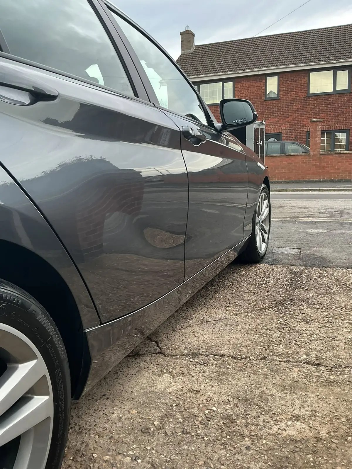 Rear door and alloy wheel of a grey BMW on a concrete drive