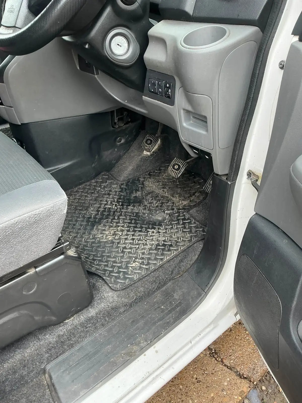 Grubby rubber floor mat and dirty pedals in a Nissan van footwell